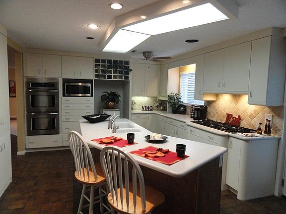 Updated kitchen offers 6 burner gas cooktop, double stainless ovens, recent microwave,solid surface counters, two pantries