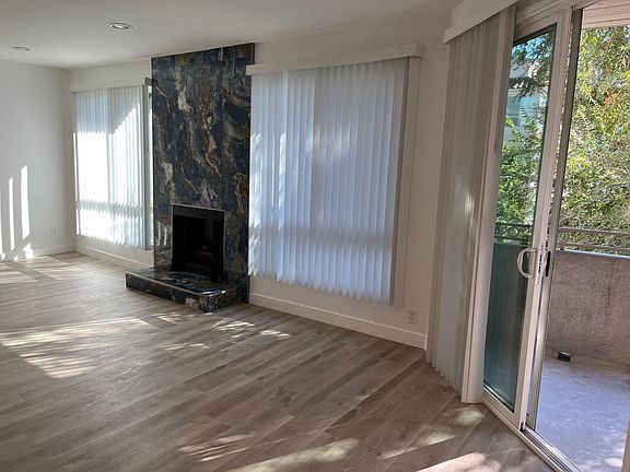 Spacious living room with access to private balcony overlooking tree lined street