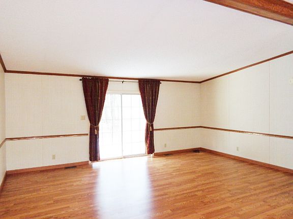 Living room open to the foyer with vaulted ceiling and newer laminate floor.