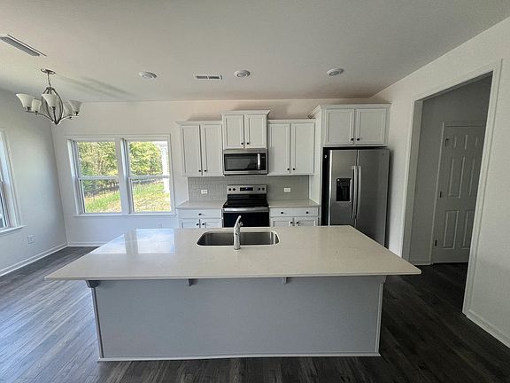 Big kitchen island with Sink and Dishwasher. Blinds are installed.