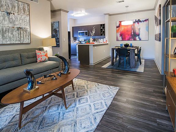 Apartment Kitchen with Stainless Steel Appliances, Dining and Living Room with wood floors.