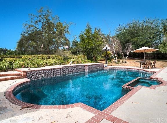 The private entertainers backyard offers a tree top view, a relaxing pool and spa, and a grassy area