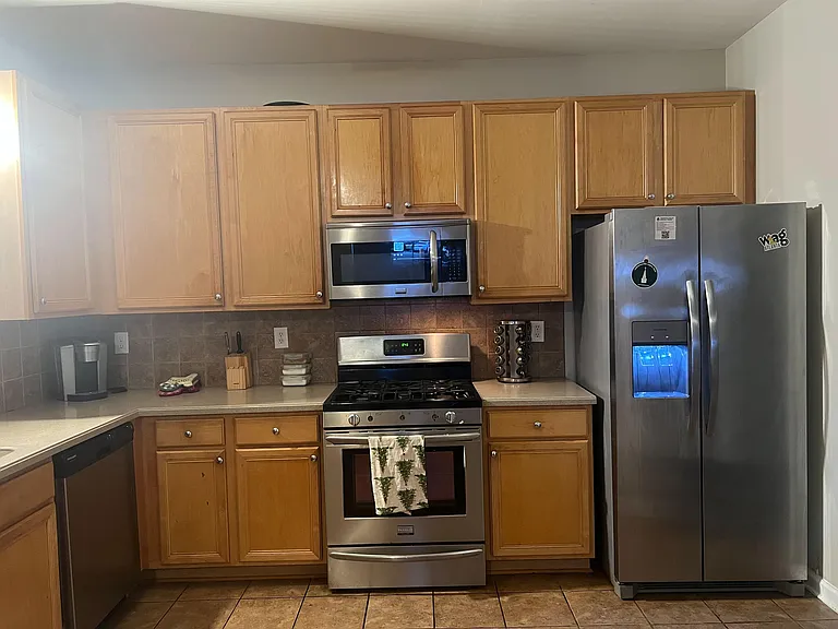 Kitchen features ample wood cabinetry, generous counter space, and stainless steel appliances including a gas range and side-