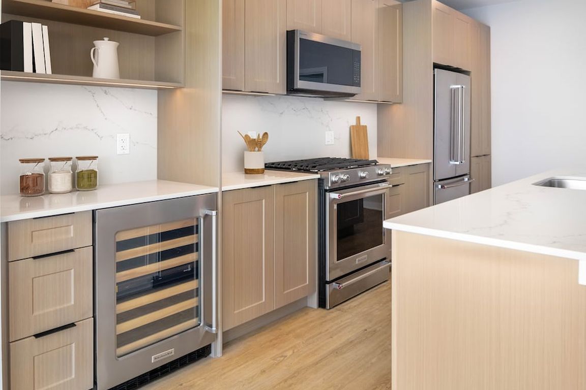 Signature Collection Kitchen with oak shaker cabinetry, marbled white quartz countertop, and upgraded stainless steel appliances