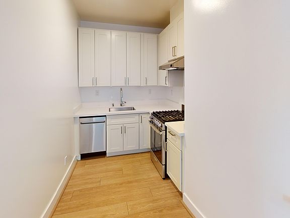 Kitchen with cabinets, stove, range hood, and sink