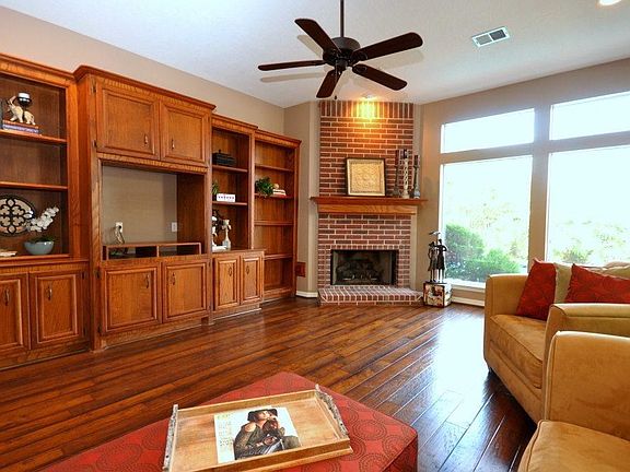 The living room shows willingly rich wood flooring accented by recessed lighting and large windows that overlook the pool.
