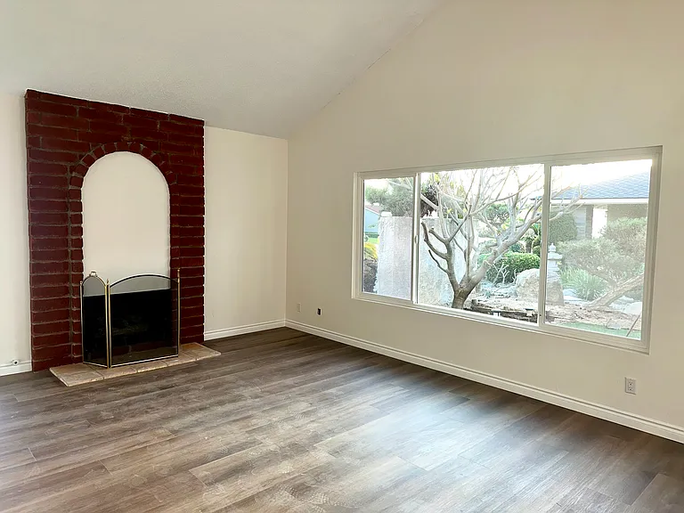 Spacious living room with fireplace, new flooring and large new windows