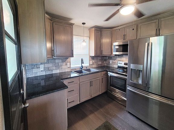 Kitchen has stained wood cabinets, granite countertops, and stainless steel appliances