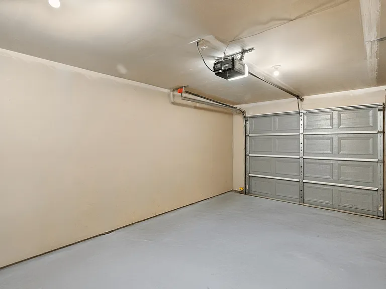 Spacious attached garage featuring an automatic door opener and clean concrete flooring. Spacious attached garage featuring an automatic door opener and clean concrete flooring.