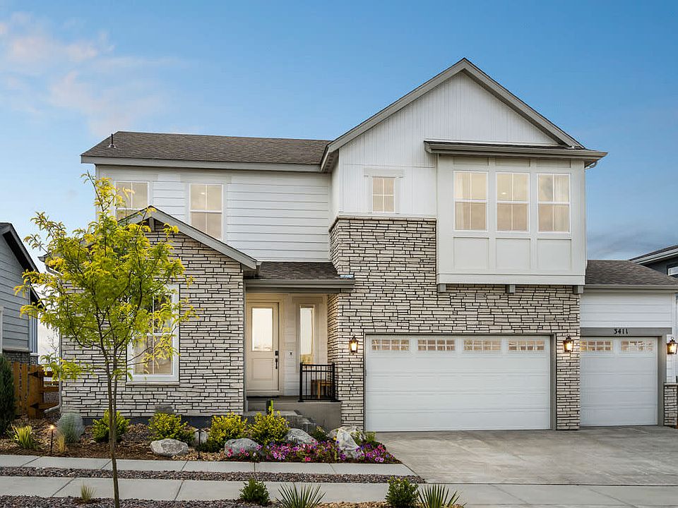 A two-story residential house with a white exterior, stone accents, and a garage door in the foregro