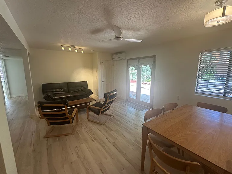 Living room with table and 6 chairs, coffee table, 2 ikea poang chairs and leather coach. Kitchen island. New ceiling fan and paint and new luxury vinyl flooring throughout unit.