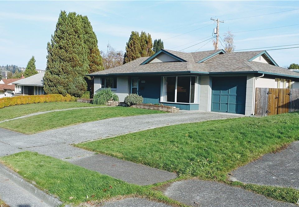 Street side of home. Notice that there are both curbs and sidewalks. And there is an ally-way in the back.  Also the gate on the right goes to the completly fenced back yard.