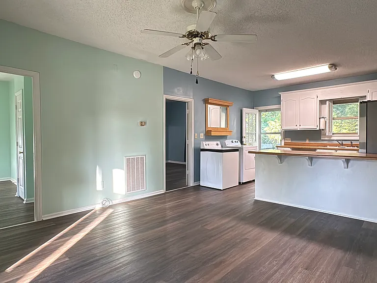 Open, airy sitting room with wood floors, flows right to the kitchen.
