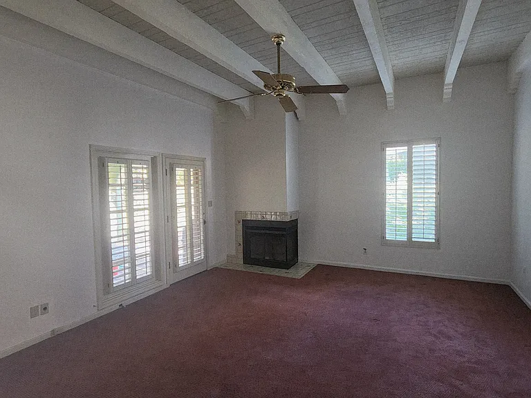 Primary Bedroom has fireplace, high beamed ceilings and access to covered patio.