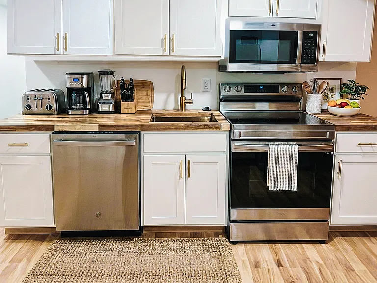 Kitchen sink and prep area with white cabinetry, clean countertops, and modern fixtures.