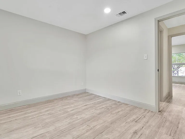 Spacious room with elegant wood-style flooring and a sunlit window view, perfect for creating a cozy living space.