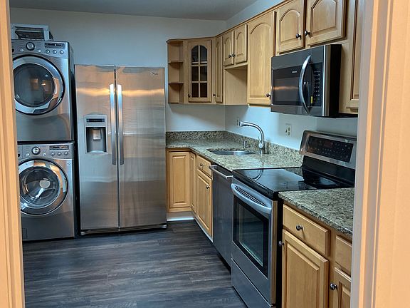 Stainless steel appliances and stacked washer and dryer in kitchen