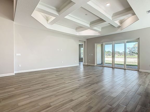 Elegant living room with quadruplet sliding glass doors leading to covered lanai and rear of property_05302024