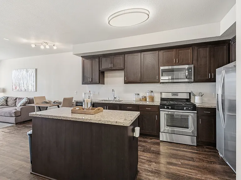 Aspire Apartments Tracy CA A modern kitchen with dark wood cabinets and stainless steel appliances.