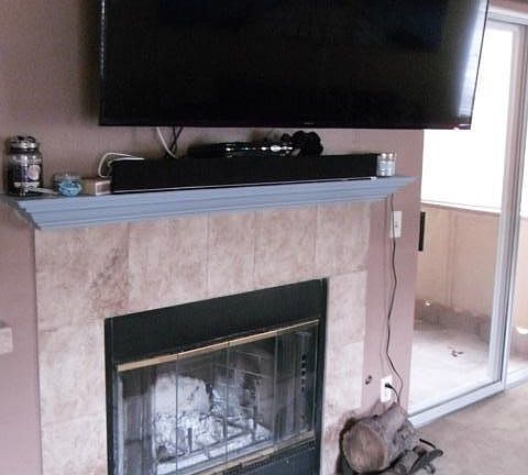Travertine-style tile gas fireplace in the living room, by the sliding door to patio...