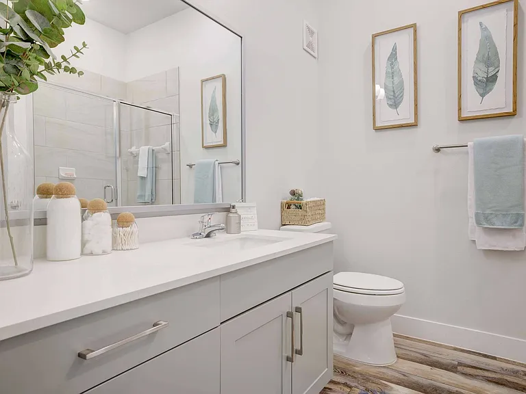 Spacious bathrooms with wood style flooring and white quartz countertops