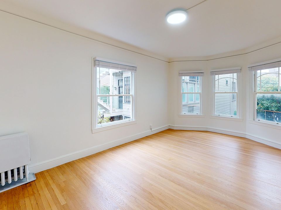 Spacious living room with wood-like flooring and a large window offering natural light