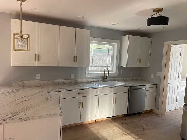 Kitchen with all new SAMSUNG appliances, white cabinetry, modern gold lighting and hardware.