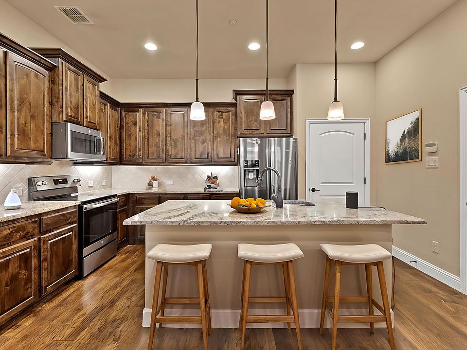 Kitchen featuring granite countertops, recessed lights, pantry, built-in cabinets, large island with pendant lighting, electric range with oven, microwave and refrigerator - virtually staged