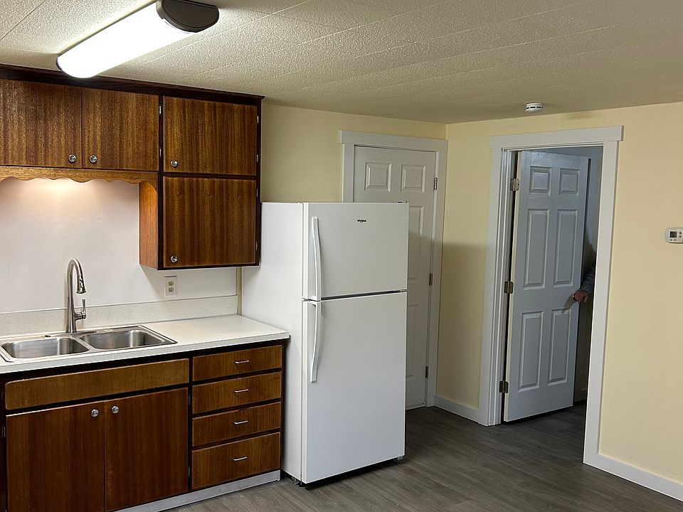 Living area into bedroom. Front door by refrigerator.
