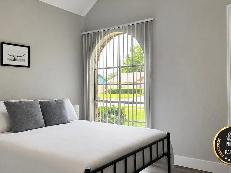 Bedroom features an arched window with vertical blinds, a comfortable bed setup, and clean neutral finishes.