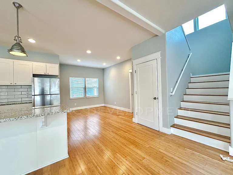 View from Living Room into Kitchen, Dining Area, Utility Closet, Broom Closet, & Staircase.