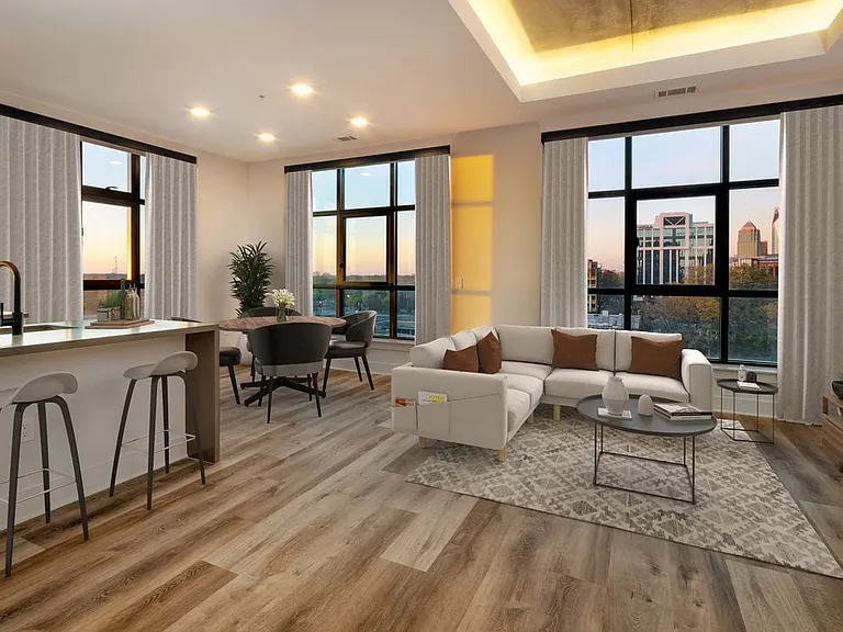 Kitchen, living, and dining areas with hard surface flooring throughout and floor-to-ceiling windows