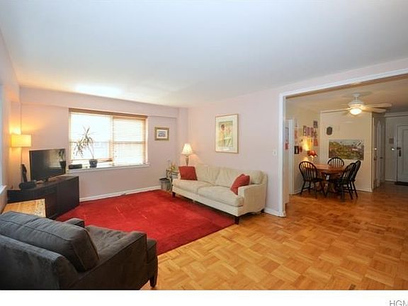 Large living room with parquet floors and two large windows featuring gorgeous tree-topped views of 