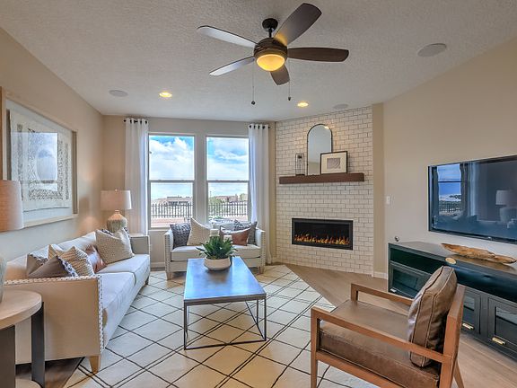 The gathering room is shown with a corner fireplace decorated with tile and a wood stained mantle.