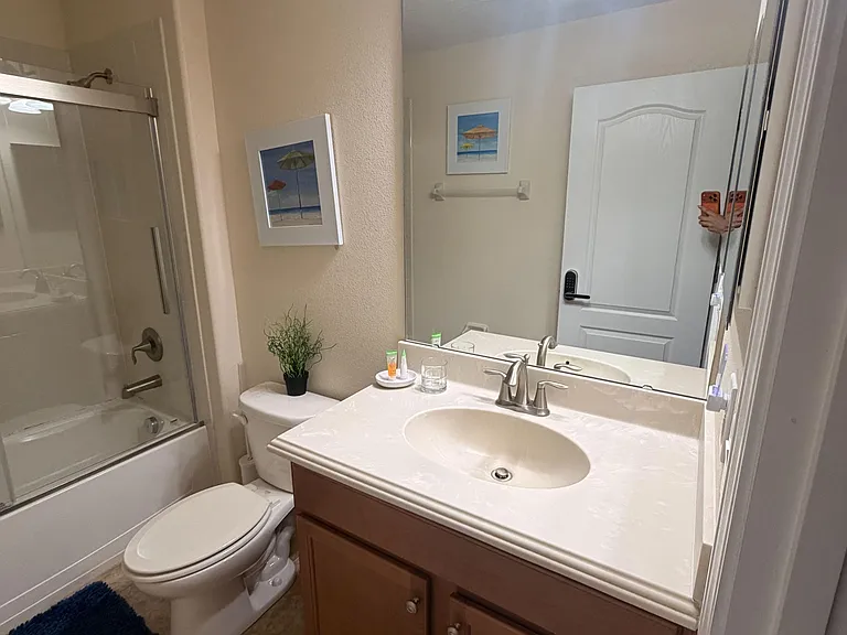 Full bathroom with tub/shower combo, spacious vanity counter, large mirror, and under-sink storage for essentials.