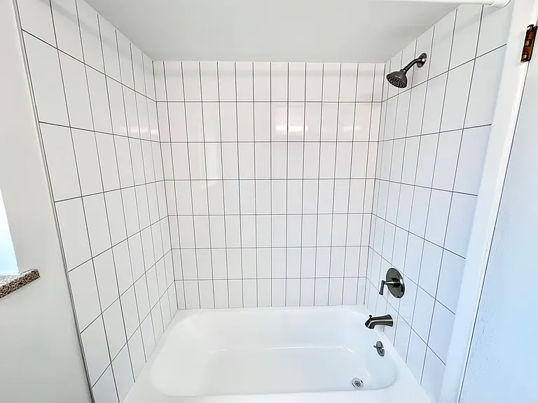 Modern bathroom with sleek white tiles and a stainless steel shower fixture. Modern bathroom with sleek white tiles and a stainless steel shower fixture.