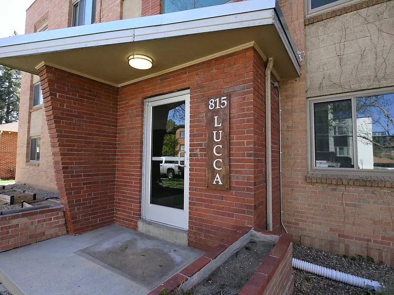 Charming red brick apartment entrance with modern design at 815 LUCCA, accented by a sleek canopy and inviting walkway.