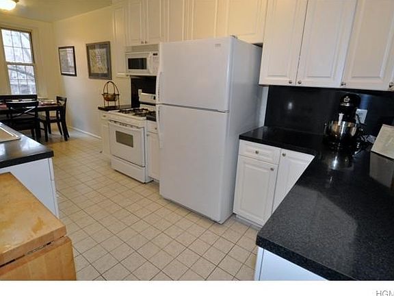 Updated eat-in-kitchen has custom cabinets and the appliances include a dishwasher, range, microwave