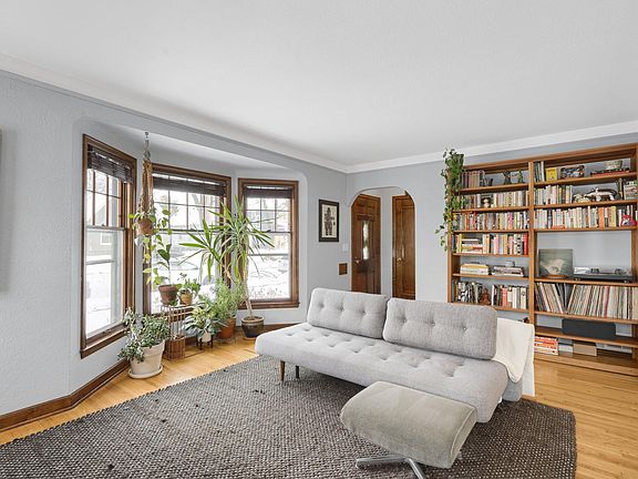 Spacious living room with refinished hardwood floors, bay window and wood-burning fireplace