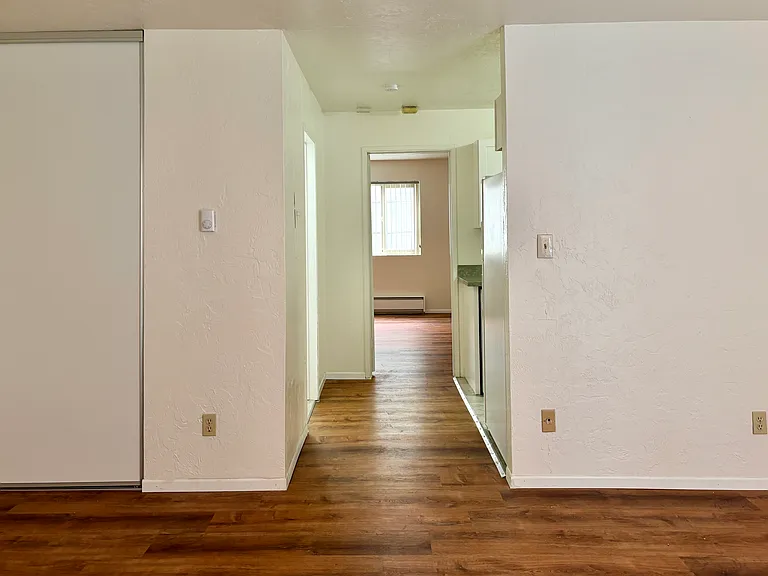 Hallway to bedroom with bathroom (left) and kitchen (right)