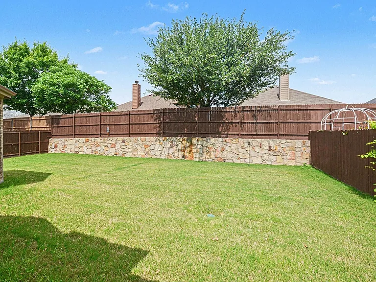 Expansive green lawn surrounded by a privacy fence