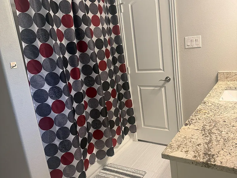 Master bathroom with a tub/shower combo, tile flooring, and a wide vanity countertop for everyday storage and prep space.