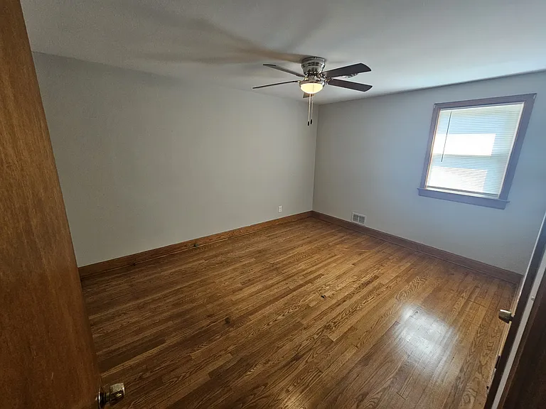 Bedroom with new ceiling fan, new paint, refinished wood floors.