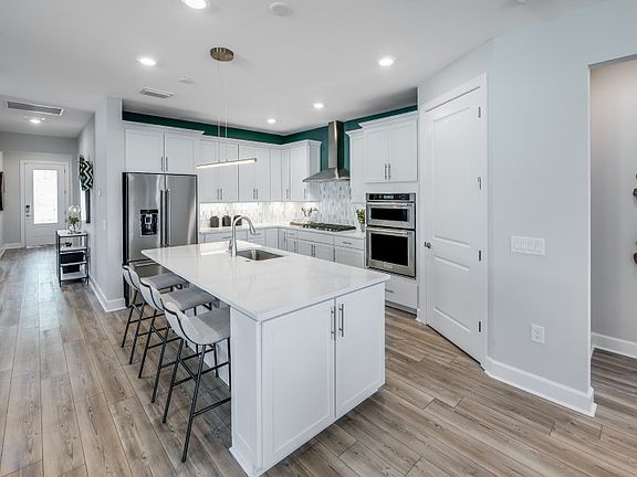 Large kitchen island with quartz countertops and white maple kitchen cabinets