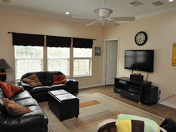 Opposite view of the family room which features ceramic tile flooring, ceiling fan and access to the master bedroom.