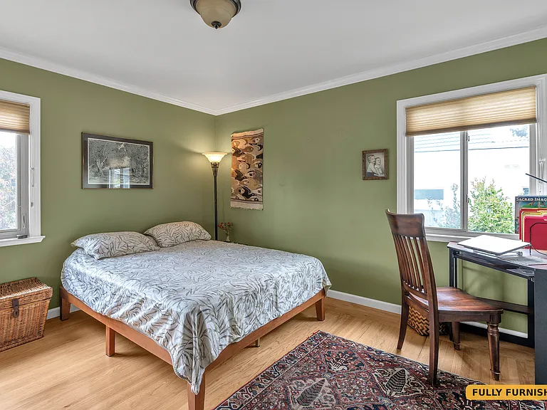 Second bedroom on the main level is furnished with a queen bed, desk and chair, large closet with sliding mirrored doors, dresser and floor lamp and has two windows and a corner desk with desk chair.