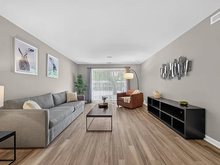 Spacious living room with Sliding Glass Door at Lakeside Village Apartments in Clinton Township, MI.