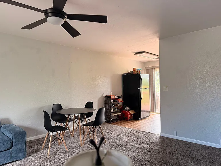 Open dining area with a table for four, ceiling fan, and easy access to the kitchen and sliding glass door.