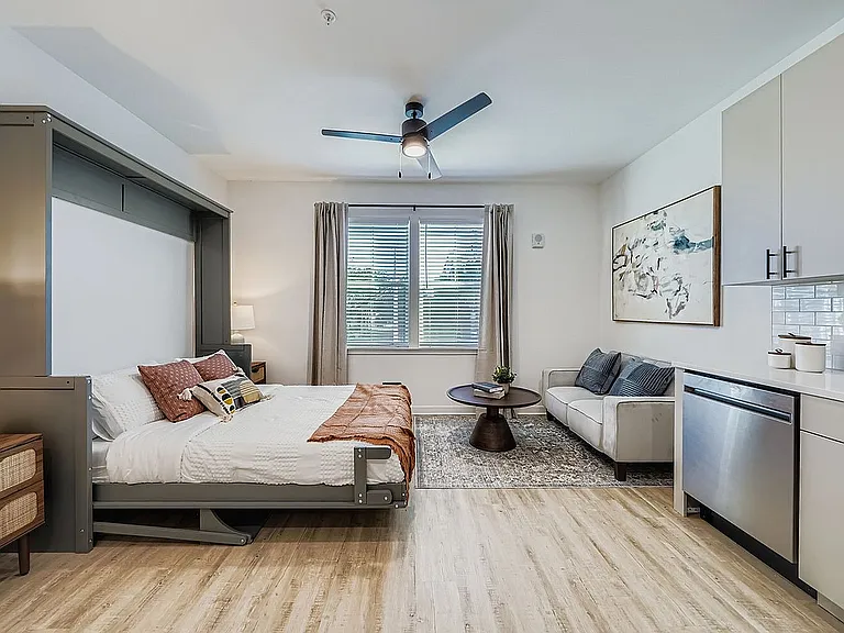 Charming studio apartment options featuring a stylish Murphy bed, cozy seating area, and modern kitchenette with natural light.