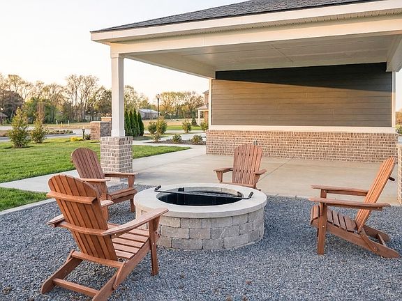 Stone Firepit behind mail kiosk, complemented by adirondack chairs and gravel area